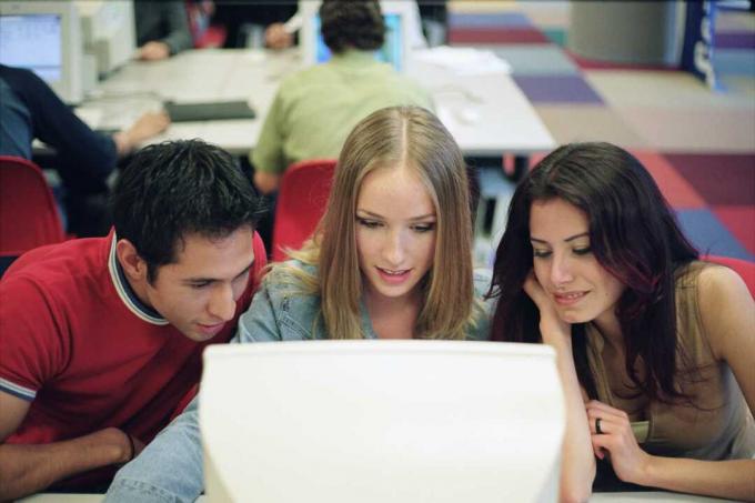 Trei studenți atenți la ecranul unei computatoare.