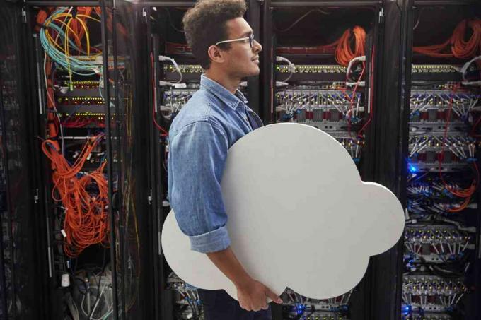 Tehnician IT de sex masculin care transportă cloud în camera serverului, cloud computing