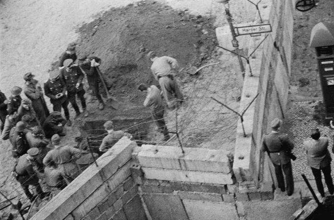 Un grup de soldați din Germania de Est investighează un tunel săpat sub zidul Berlinului.