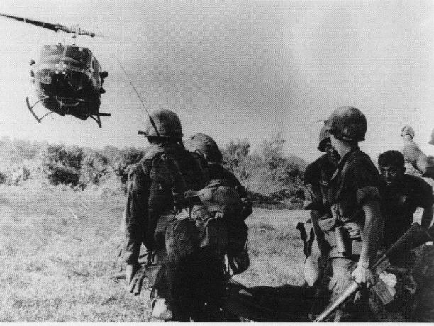UH-1 Huey elicopter aterizat lângă un grup de soldați.
