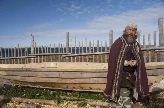 Actor viking în îmbrăcăminte tipică în fața replicii pentru bărci cu barcă lungă, L’Anse Aux Meadows, Newfoundland