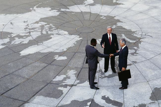  Regionalism economic: oameni de afaceri strâng mâna pe harta globului.