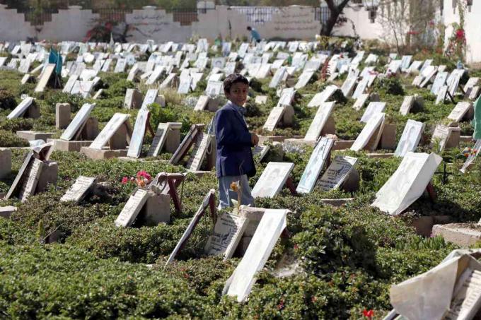 Un copil se plimbă printre morminte de oameni care au fost uciși în războiul continuu la un cimitir din Sana’a, Yemen.