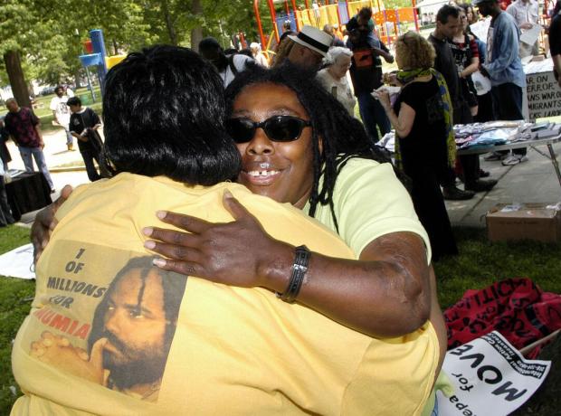 Ramona Africa (R), singura supraviețuitoare a tragediei din MOVE din 1985, o îmbrățișează pe Denise Garner (L) în timpul unui marș comemorativ din 2005